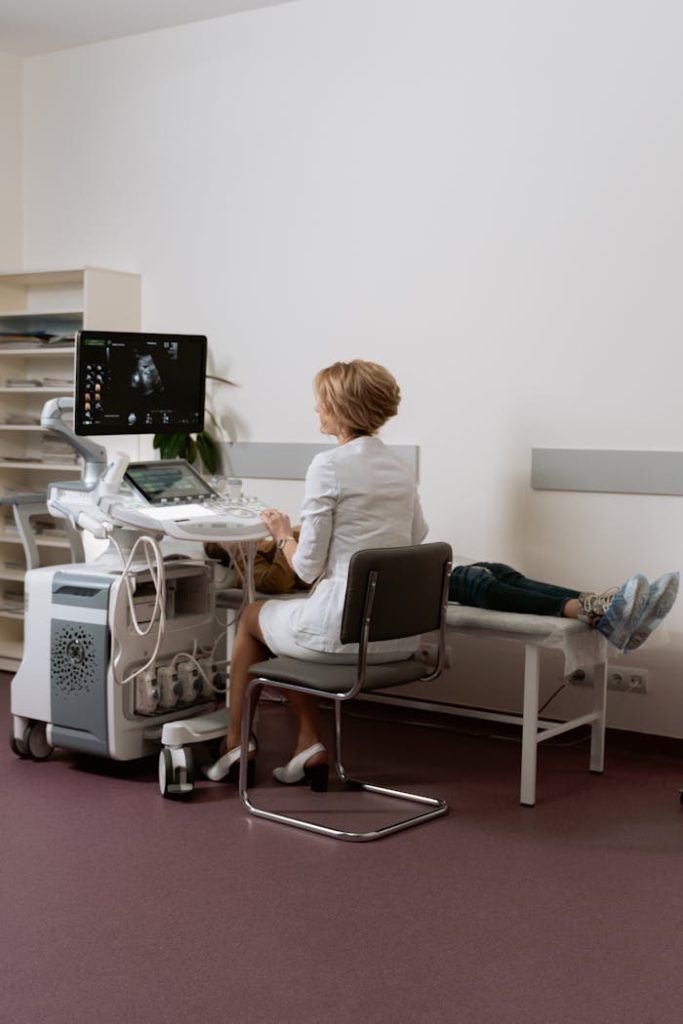 Doctor conducting ultrasound scan on pregnant woman in a clinic setting.